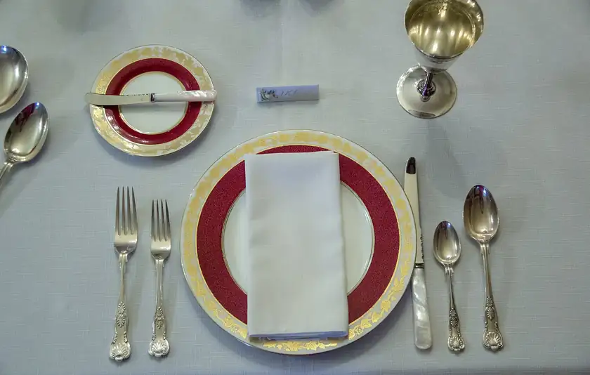 A long dining table set with plates and glasses and no people seated