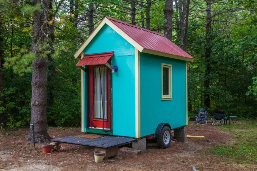 A small wooden tiny house with a metal roof and a covered front porch