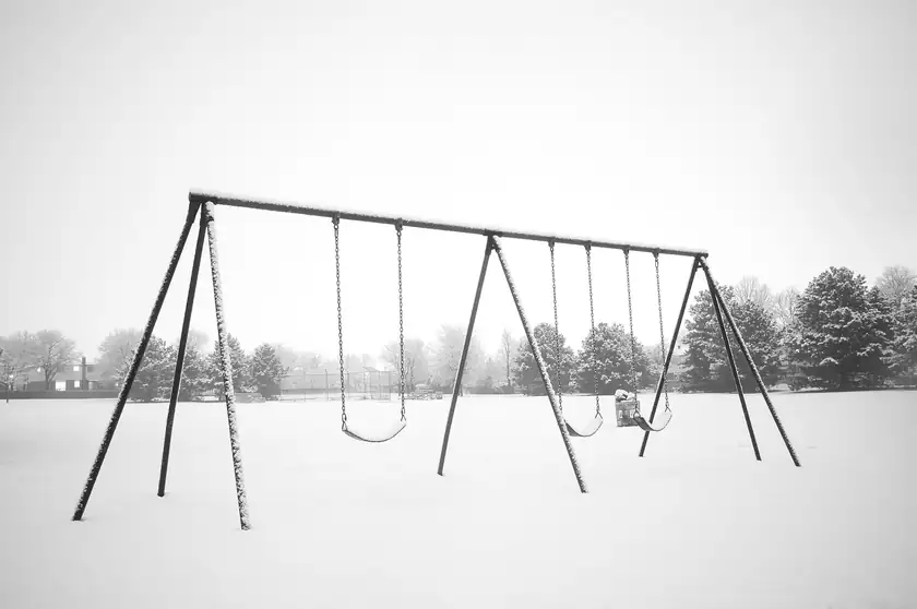 An empty playground with a slide and climbing bars and no children in the frame