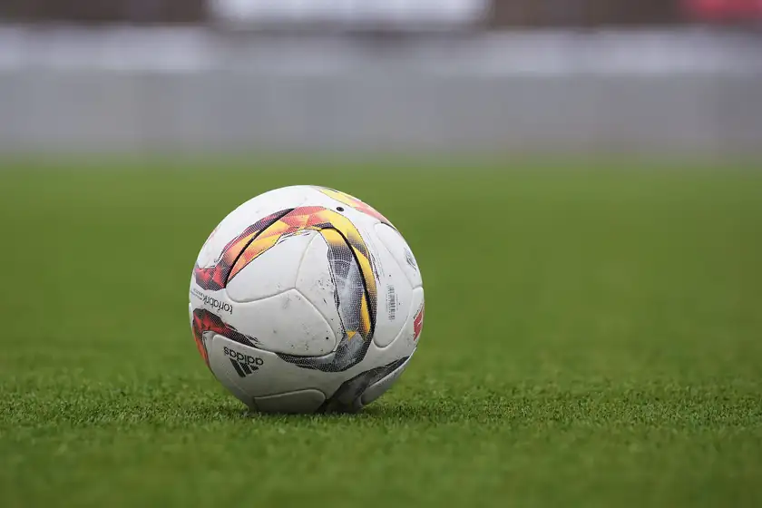 A white soccer ball with black panels resting on green grass