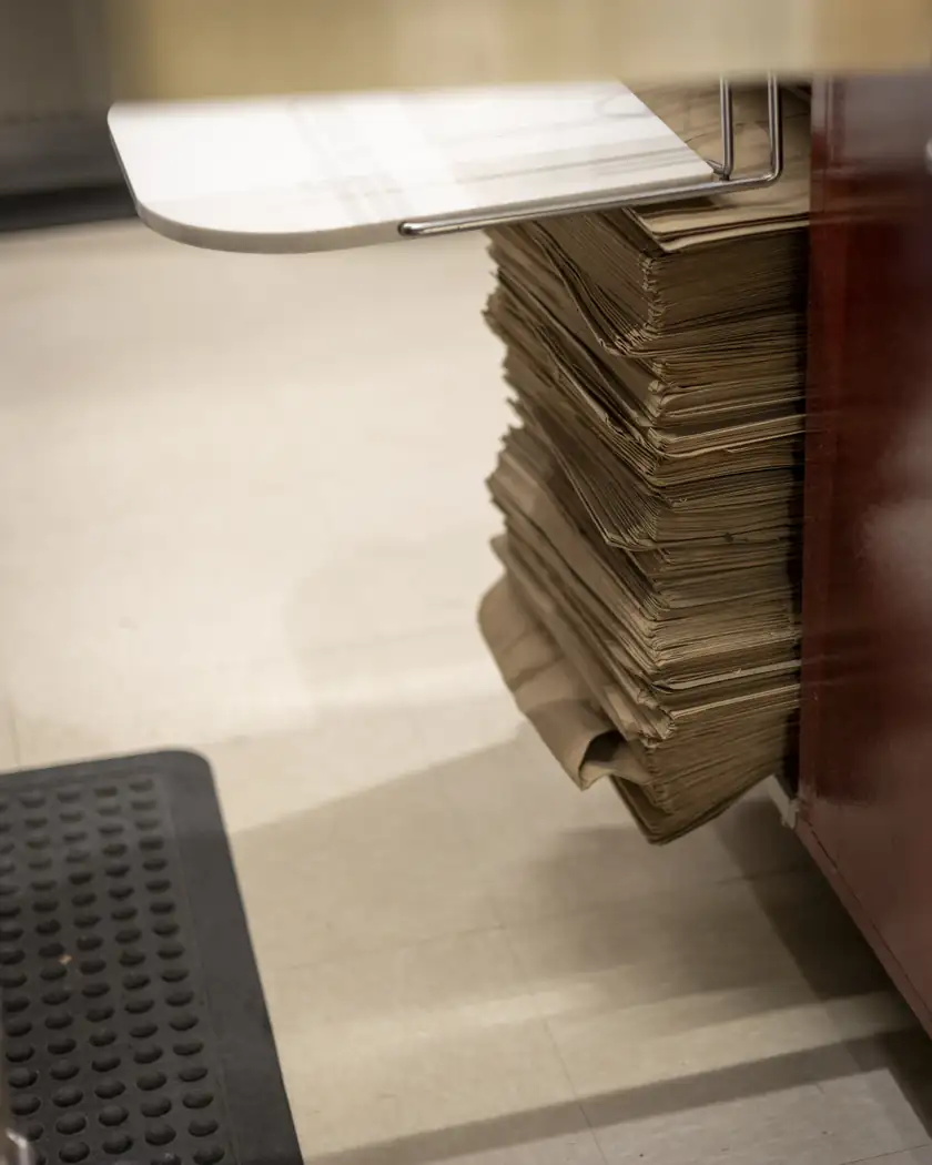 A tall stack of brown paper grocery bags under a counter