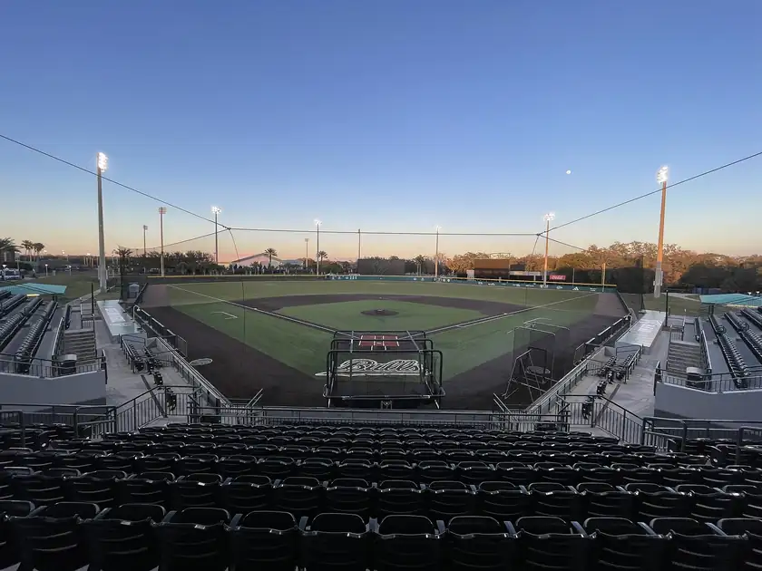 An empty college baseball stadium with a green outfield and no players