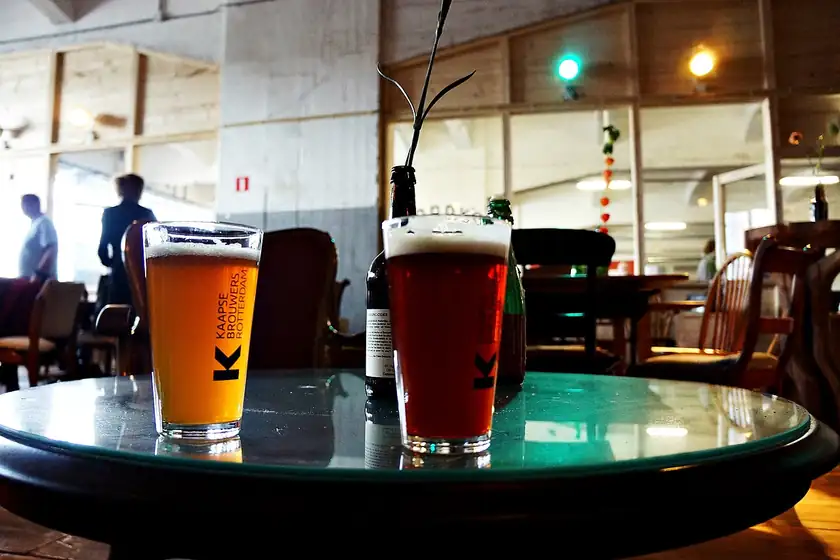 Several glasses of beer sitting on a wooden table