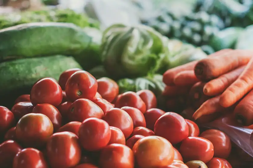 A pile of fresh vegetables including peppers, tomatoes, and leafy greens
