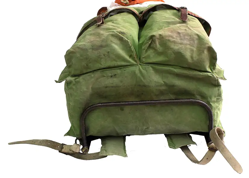 A black backpack with brown leather straps standing against a white background