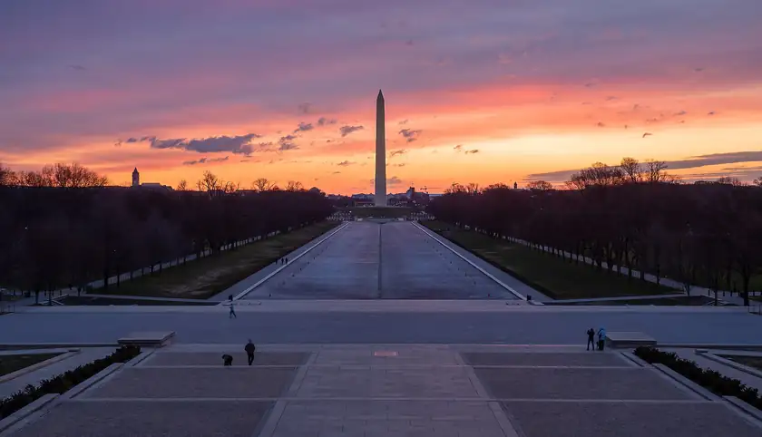 The Washington Monument at sunrise against a pink sky, with no crowd