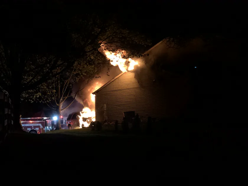 Flames and smoke pouring from a two-story house at night