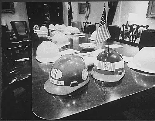Several hard hats lined up on a wooden table, with no people