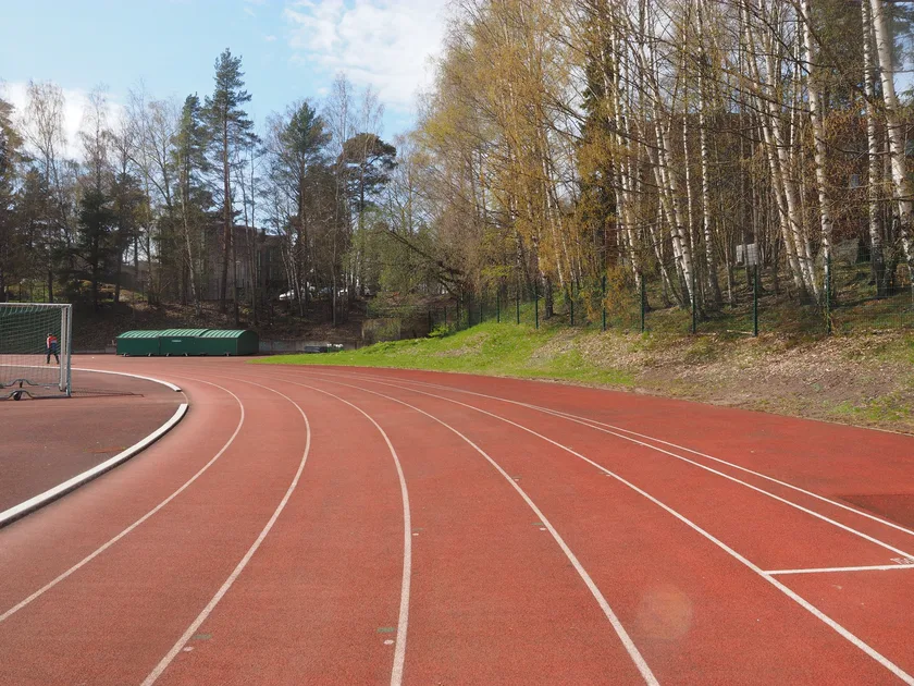 A red running track curving through a green sports field