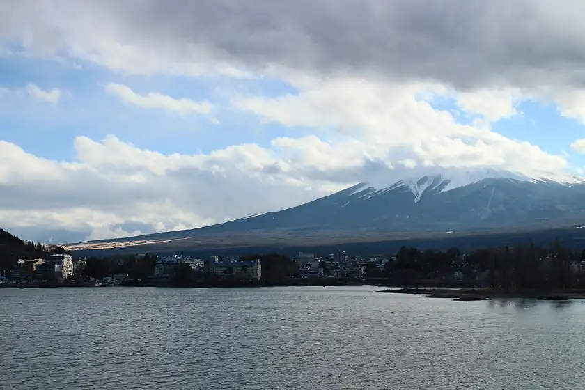 Mount Fuji across a lake, with a shoreline and no people in the foreground
