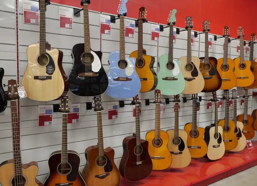 A row of acoustic guitars standing on the floor of a music store
