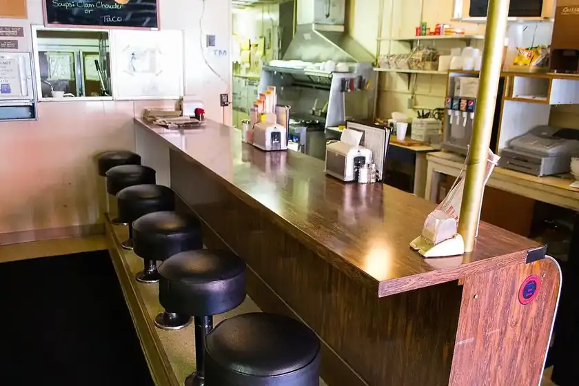An empty lunch counter with six stools and pendant lights
