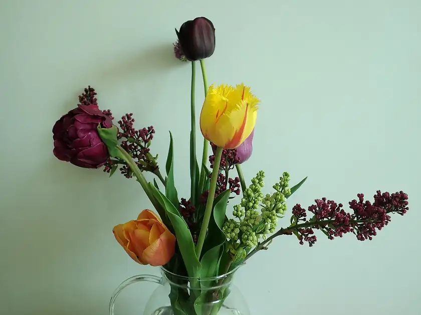 A bouquet of pink tulips and purple lilacs in a glass vase