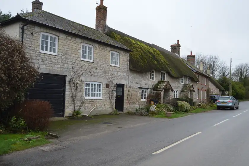 A row of small brick cottages with dark roofs and no people in front