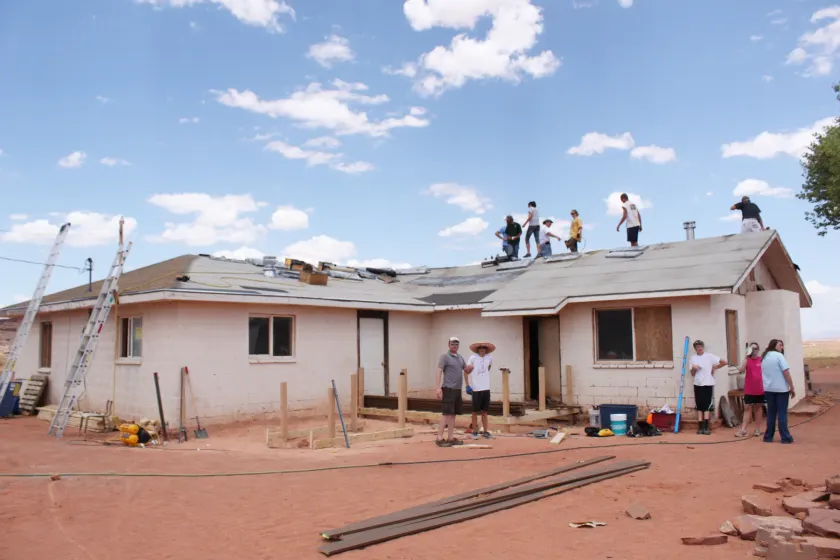 Volunteers framing a wooden porch and wheelchair ramp beside a house
