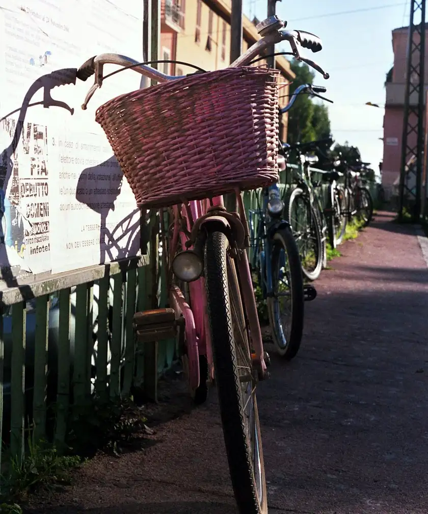 A pink bicycle parked on a sidewalk with no rider
