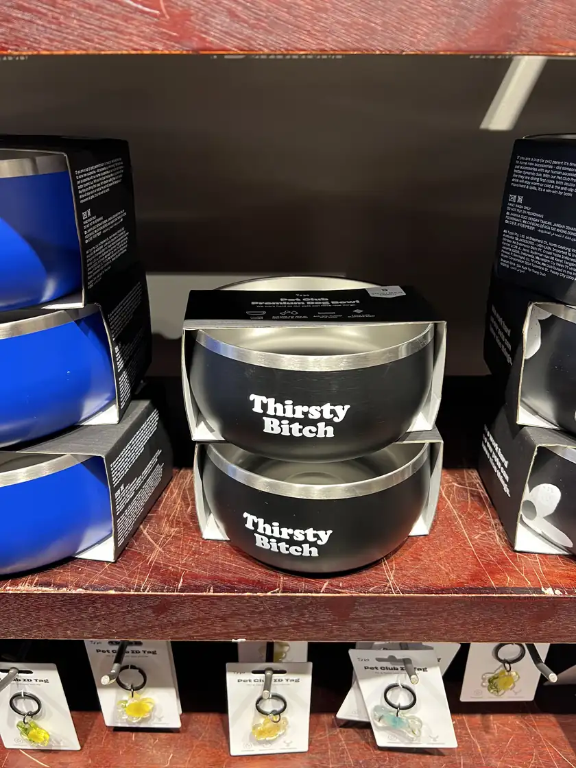 Three empty metal dog bowls sitting on a concrete floor