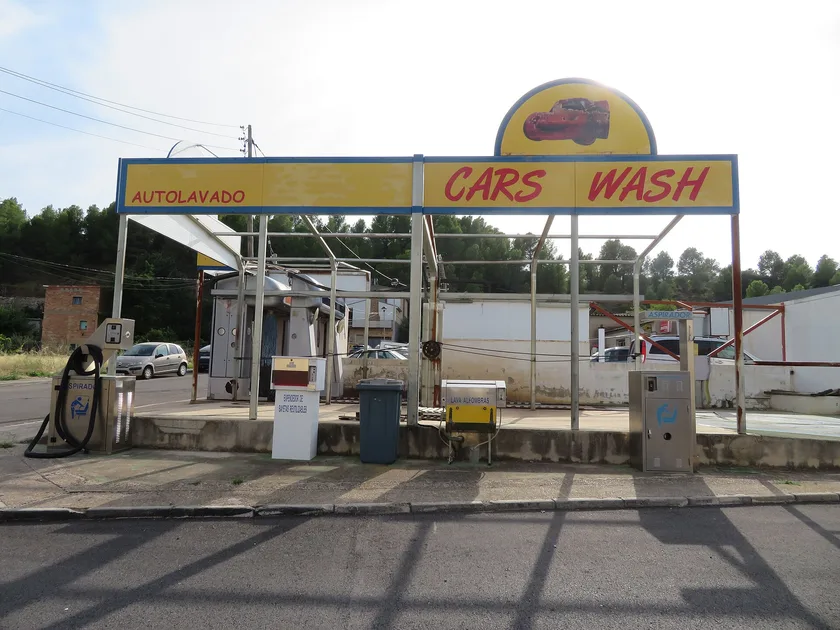 A small roadside car wash with a yellow sign reading Cars Wash
