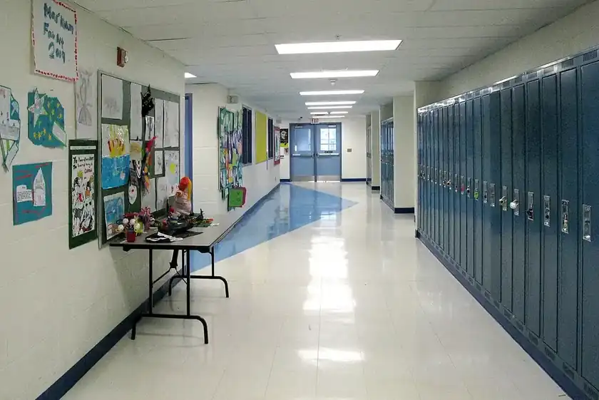 A bright school hallway lined with blue lockers and a shiny floor