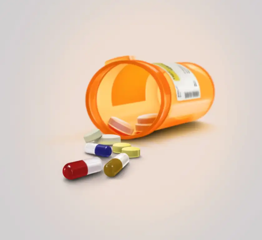 White tablets spilled from an amber prescription bottle onto a white surface