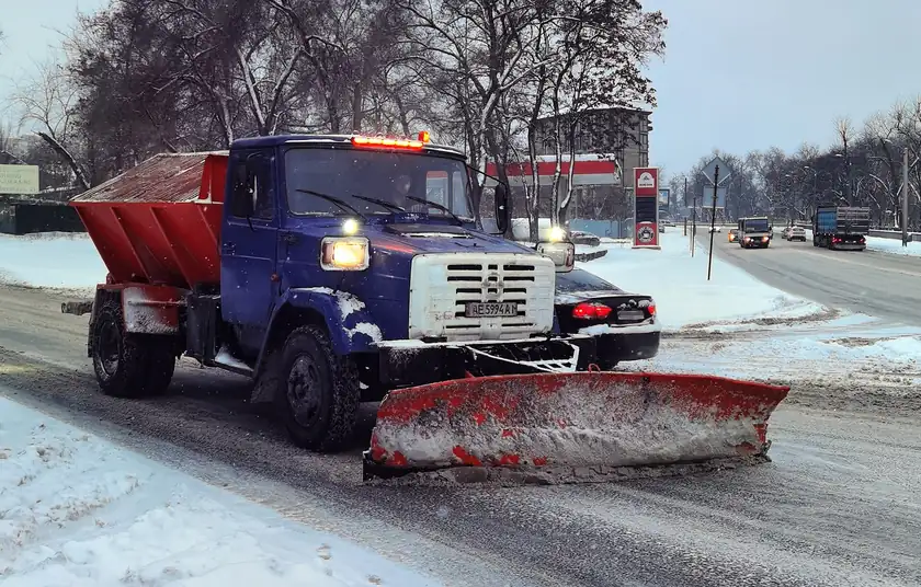 An orange municipal truck with a snowplow blade, parked with no one beside it