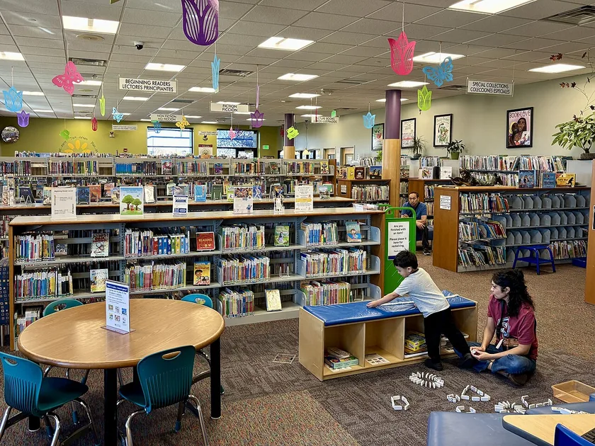 Low wooden shelves of children's books in a bright library room