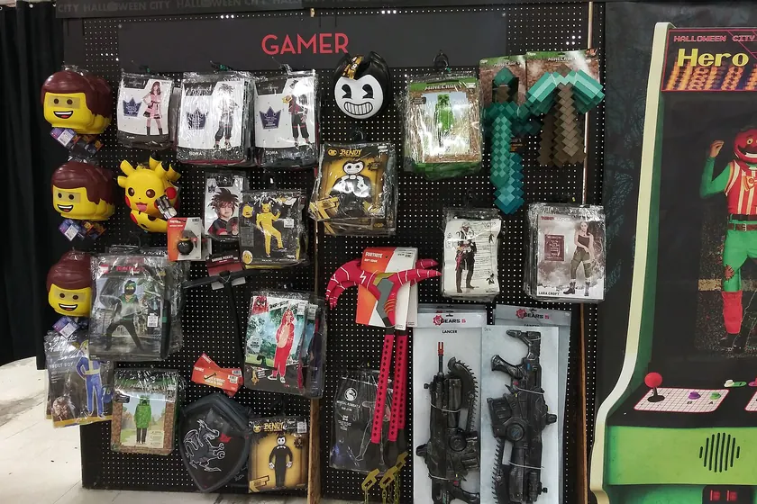 A store aisle of packaged Halloween costumes under a sign that reads Gamer
