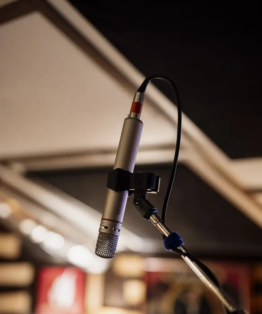 A studio microphone on a stand against a dark background, with no singer