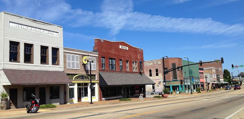 Brick and painted storefronts along a street in downtown Tupelo on a sunny day