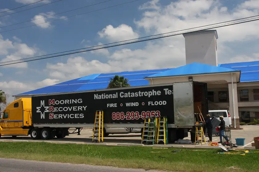 A bright blue tarp covering most of a damaged roof